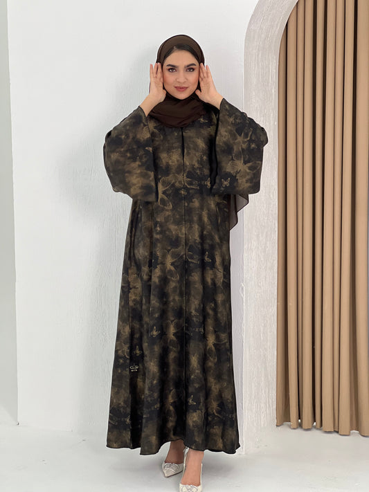A woman wearing an Abstract Bronze Black Satin printed abaya with long sleeves and a round neckline.