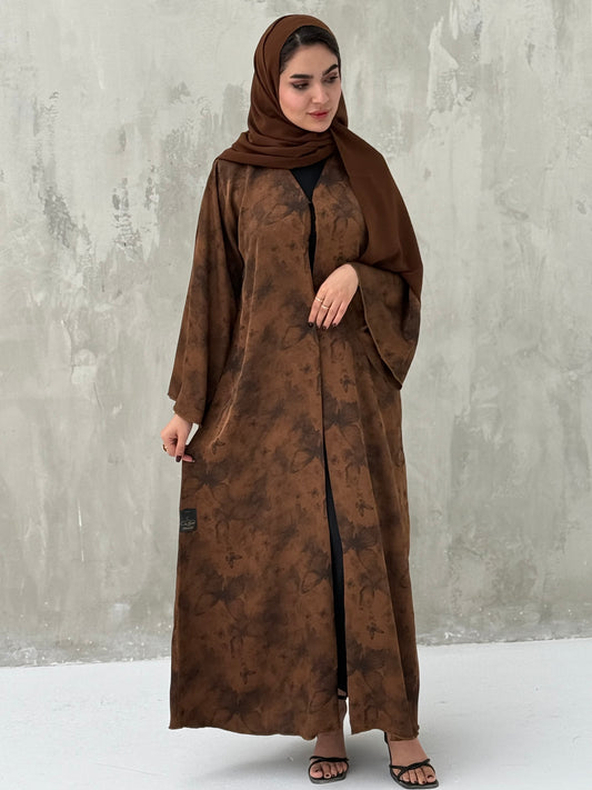 A woman wearing a Brown Printed Satin abaya with long sleeves and a round neckline.
