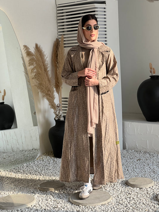 A woman wearing a Beige Printed Trench coat style with buttons and pockets in an indoor setting