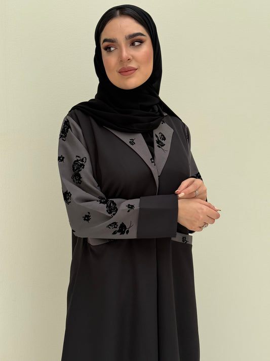 A woman wearing a Black & Grey Velvet Floral abaya with velvet and Barbie fabric.