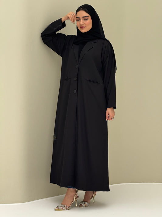 A woman wearing a black Coat style with a lapel collar, Button-front, welt pockets, buttoned cuffs, and a matching sheila