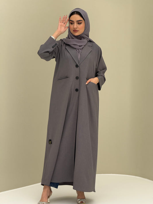 A woman wearing a dark grey Coat style with a lapel collar, Button-front, welt pockets, buttoned cuffs, and a matching sheila