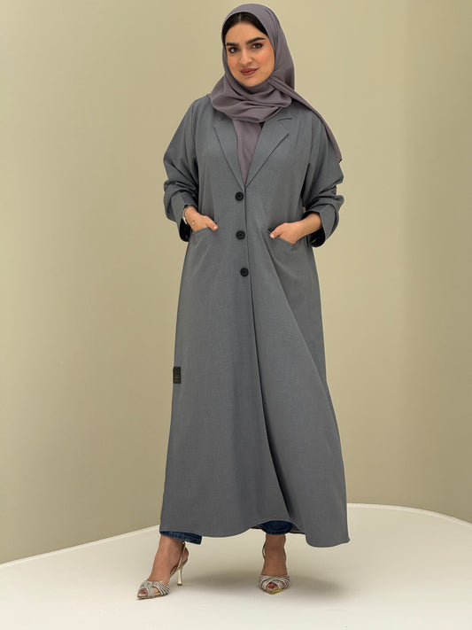 A woman wearing a light grey Coat style with a lapel collar, Button-front, welt pockets, buttoned cuffs, and a matching sheila