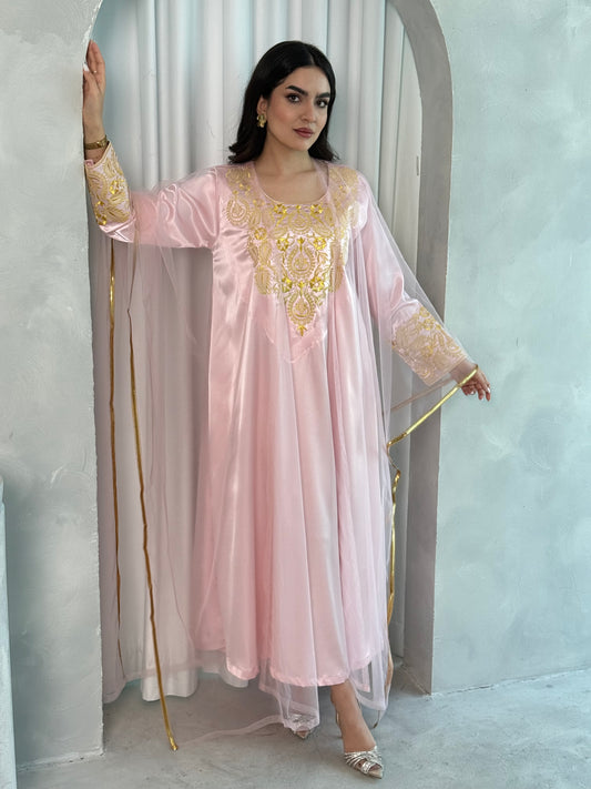 A person wearing a pink and gold embroidered maxi dress with netting, posing indoors.