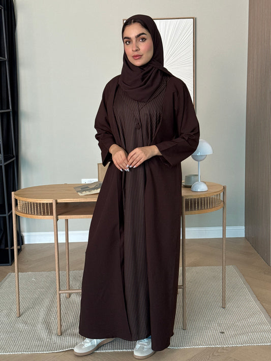 Person wearing a long Dark Brown Pinstripe Linen Abaya with a matching sheila standing in a room with a mirror.