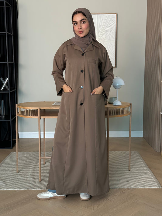 Woman wearing a brown Linen Pocket Abaya coat with a matching sheila in an indoor setting