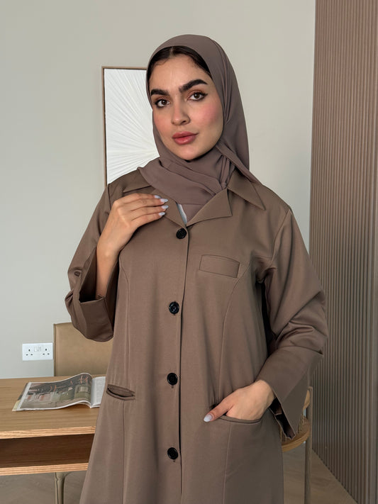 Woman wearing a brown Linen Pocket Abaya coat with a matching sheila in an indoor setting