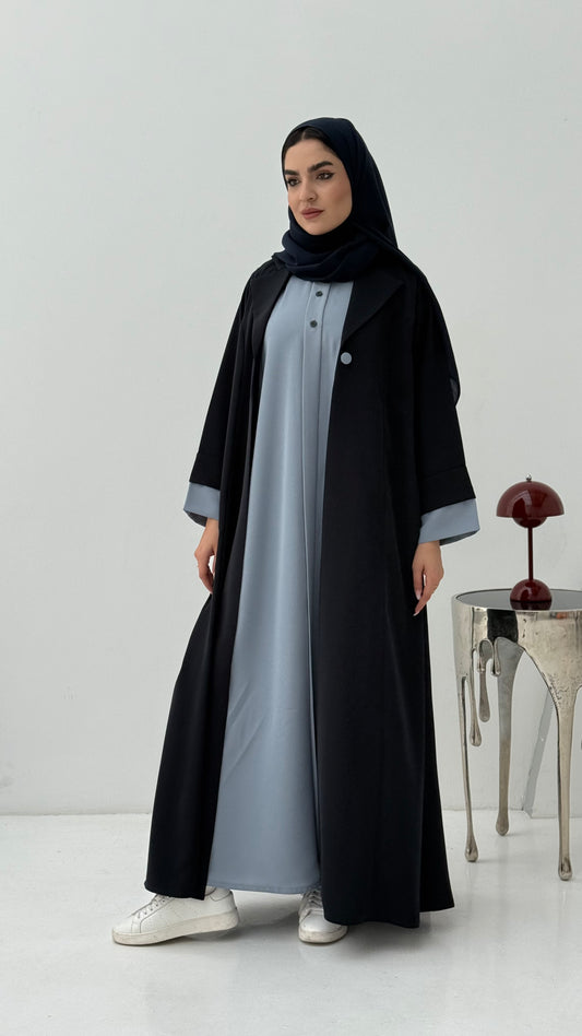 Woman wearing a Navy Blue Abaya with a light gray overlay on a white background