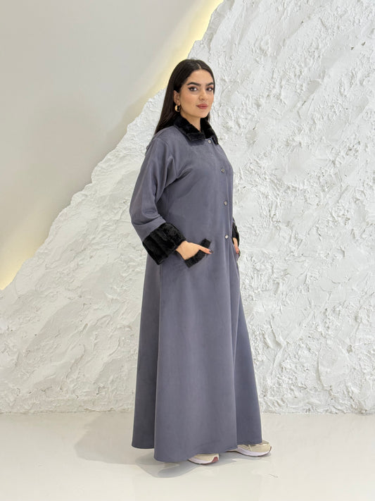Woman in a long Steel Grey Shamwa Abaya standing on a textured white surface
