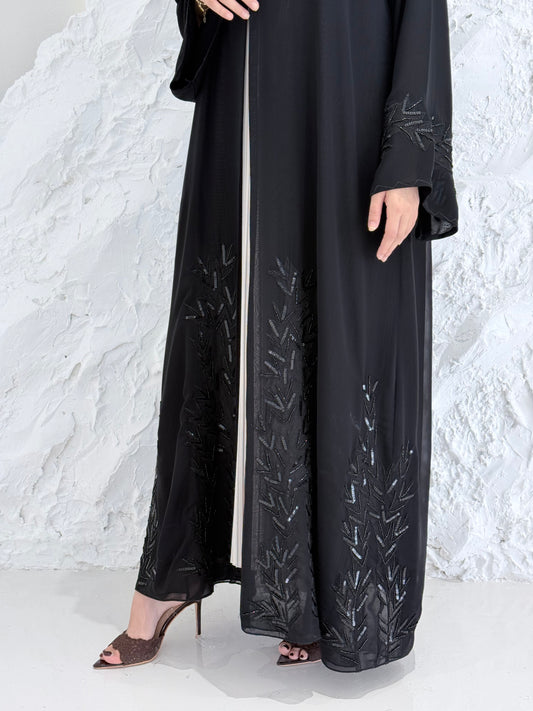 Woman in a long Premium Black Hand-Embellished Chiffon Abaya standing on a snowy landscape