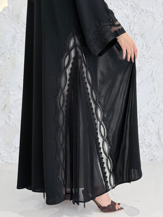 Woman wearing a Premium Black Abaya with Black Plissé Panel on a light gray background