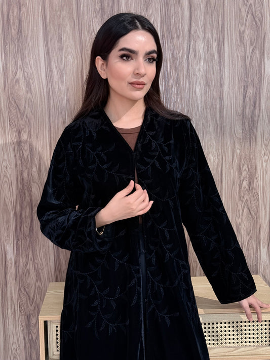 a woman wearing Premium Black Velvet Abaya with Tone-on-Tone Vine floral Embroidery on a pink background