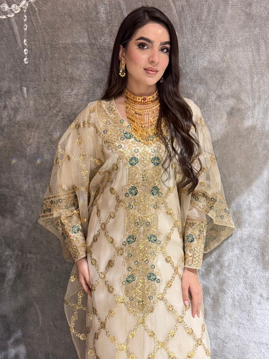 Woman wearing a traditional Beige Luxury Embroidered Kaftan outfit on a textured gray background