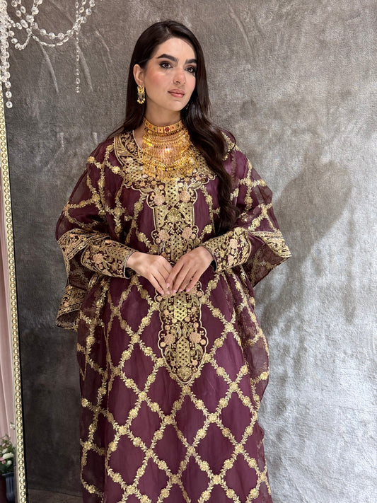 Woman in a Maroon Luxury Embroidered Kaftan traditional outfit standing on a textured surface.