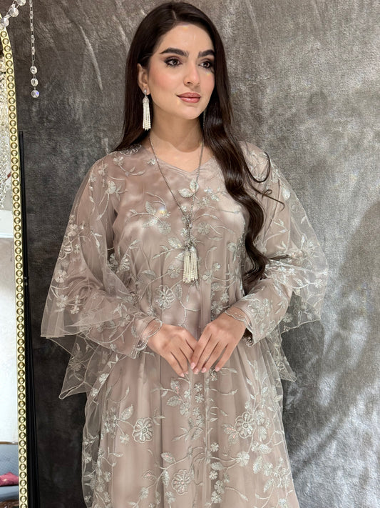 Woman in a Dusty Beige Floral Embroidered Kaftan standing in front of a mirror with a chandelier in the background