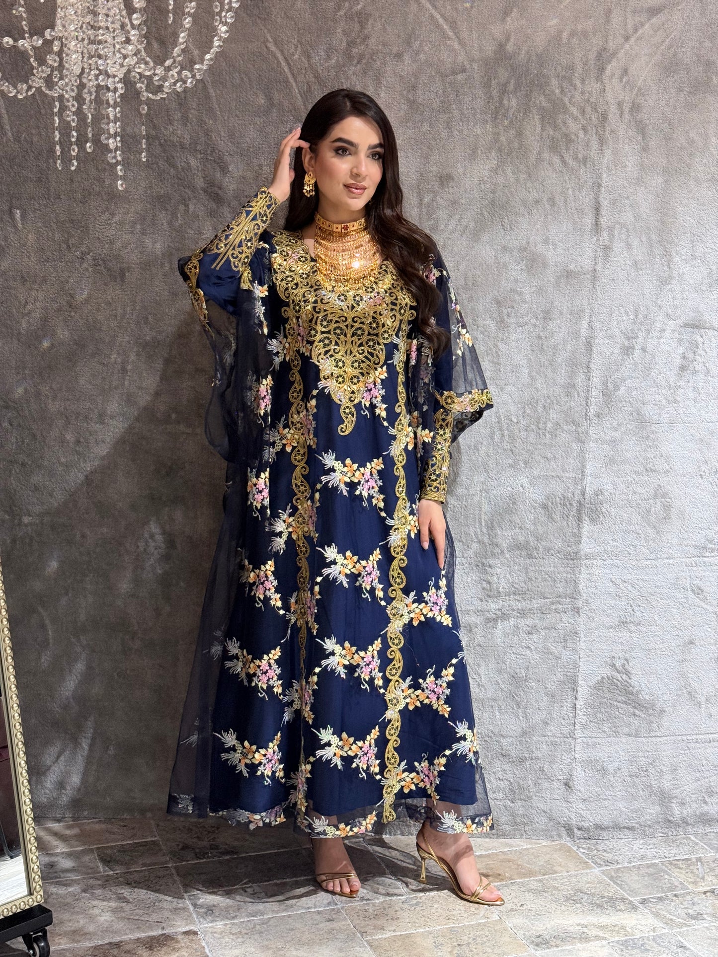 Woman in a O 285 Navy Luxury Embroidered Kaftan standing on a reflective floor.