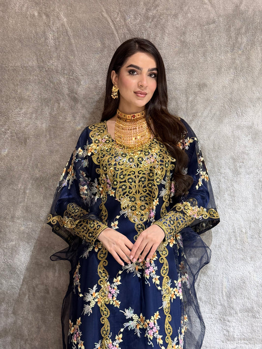 Woman in a O 285 Navy Luxury Embroidered Kaftan standing on a reflective floor.