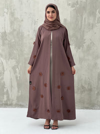 A woman wearing a Cinnamon Brown Chiffon Abaya with floral patterns and a matching brown headscarf.