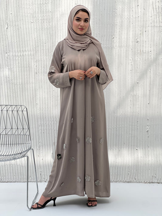 A woman wearing a Light Brown Chiffon Abaya with floral patterns and a matching brown headscarf.