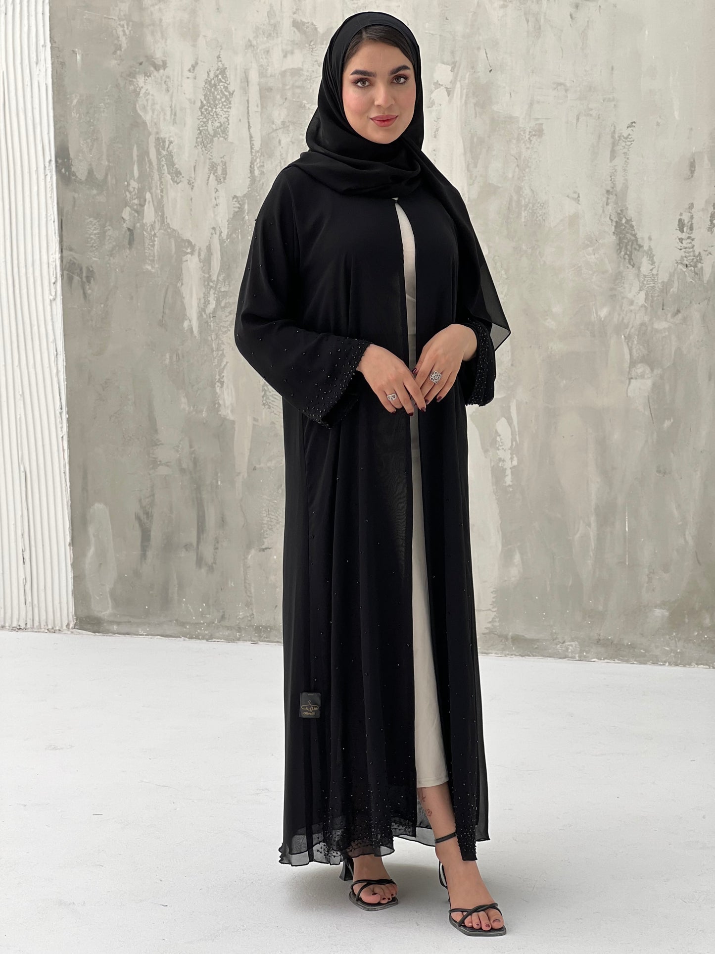 A woman wearing a Black Chiffon Abaya with Crystal Beads with long sleeves and a matching headscarf.