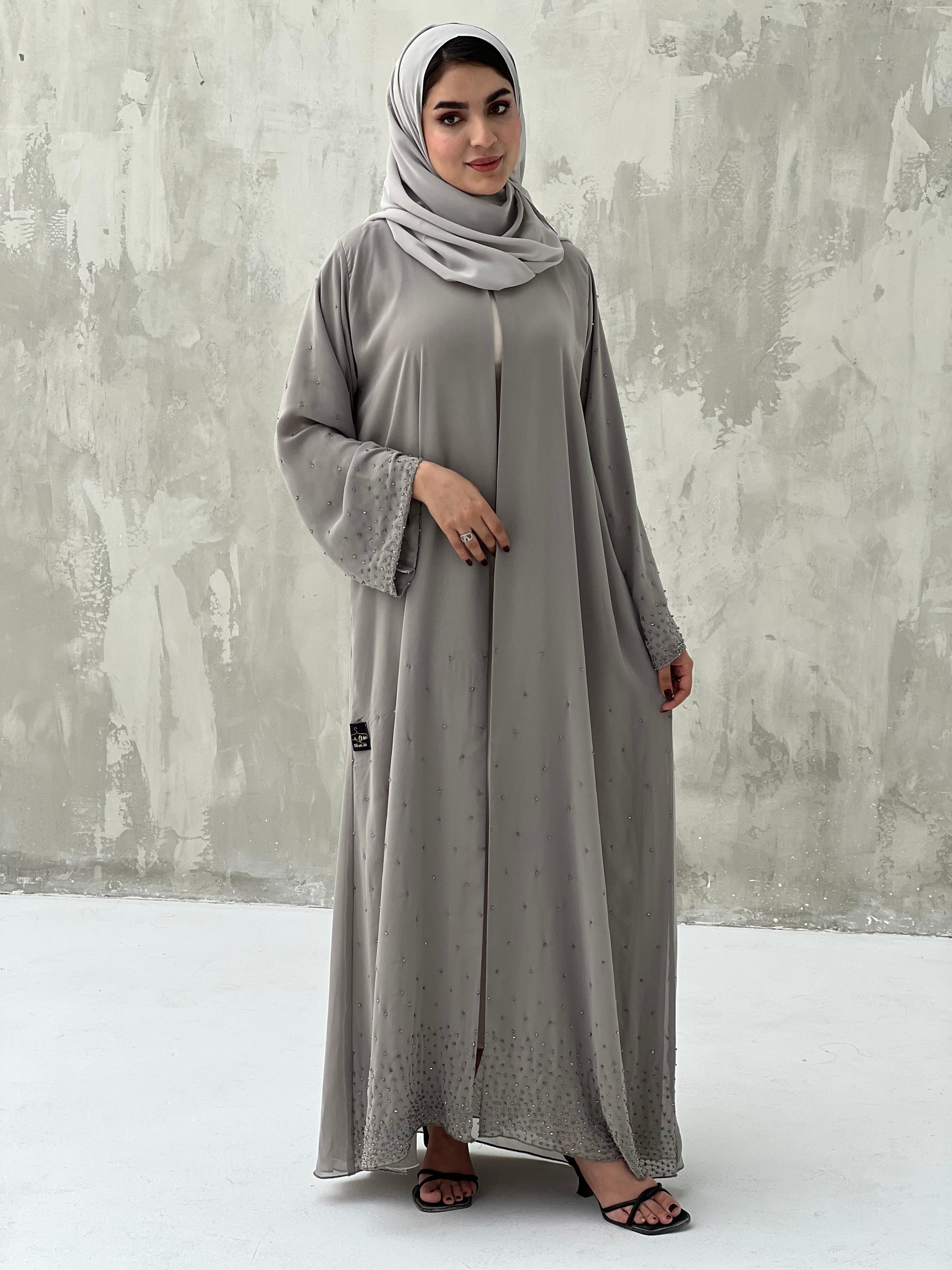 A woman wearing a Grey Chiffon Abaya with Crystal Beads with long sleeves and a matching headscarf.