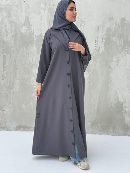 A woman wearing a Dark Grey Coat-Style Abaya with buttons down the front, paired with a matching headscarf.