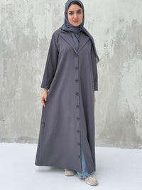 A woman wearing a Dark Grey Coat-Style Abaya with buttons down the front, paired with a matching headscarf.
