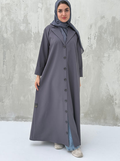 A woman wearing a Dark Grey Coat-Style Abaya with buttons down the front, paired with a matching headscarf.