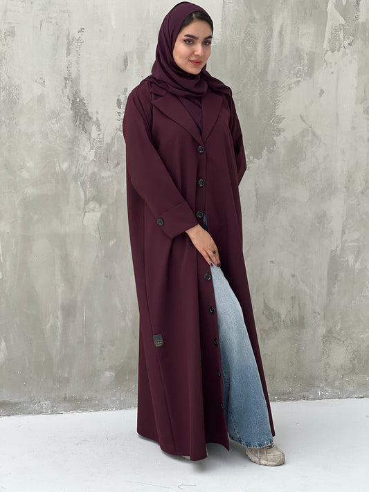 A woman wearing a Maroon Coat-Style Abaya with buttons down the front, paired with a matching headscarf.