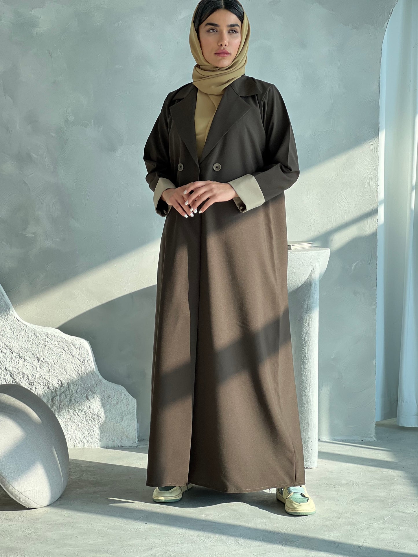 A woman wearing a Dark Olive Blazer-Style Abaya with long sleeves and a matching Sheila, standing indoors.