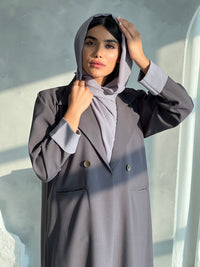 A woman wearing a Slate Grey Blazer-Style Abaya with long sleeves and a matching Sheila, standing indoors.