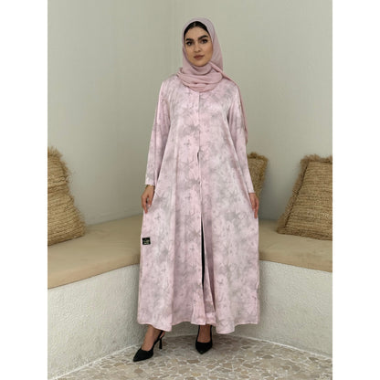 A woman wearing a baby Pink Printed Satin printed abaya with long sleeves and a round neckline.