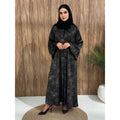 A woman wearing a black and gray printed abaya with long sleeves and a round neckline.