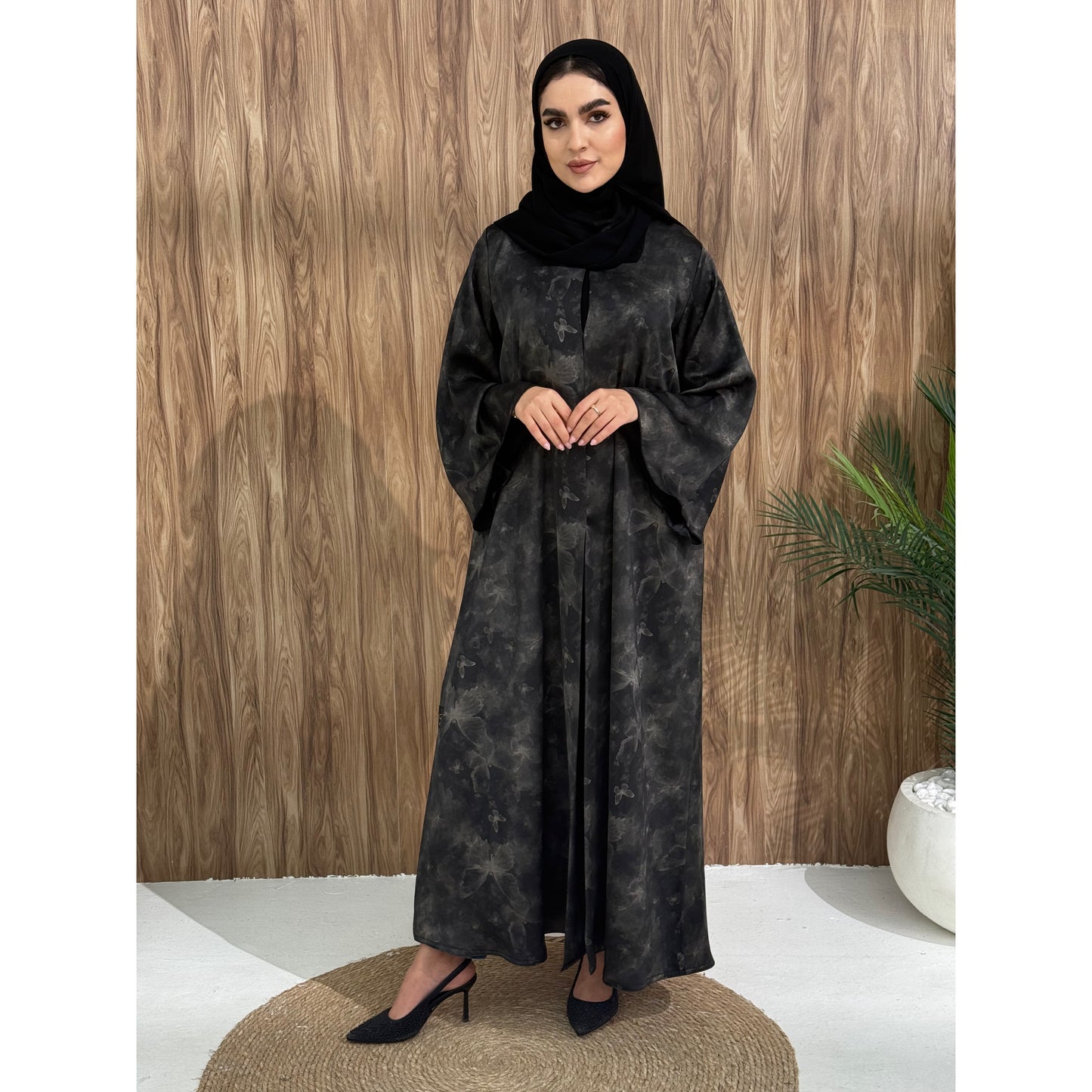 A woman wearing a black and gray printed abaya with long sleeves and a round neckline.