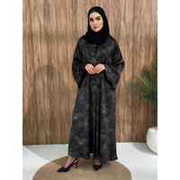 A woman wearing a black and gray printed abaya with long sleeves and a round neckline.