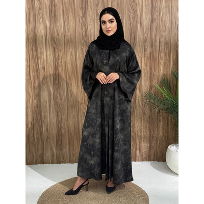 A woman wearing a black and gray printed abaya with long sleeves and a round neckline.