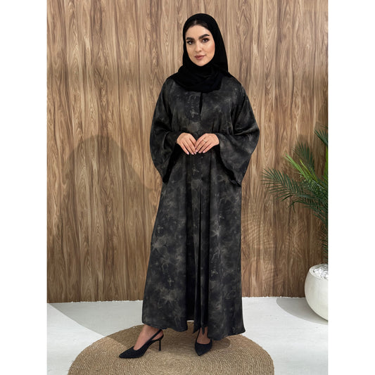 A woman wearing a black and gray printed abaya with long sleeves and a round neckline.