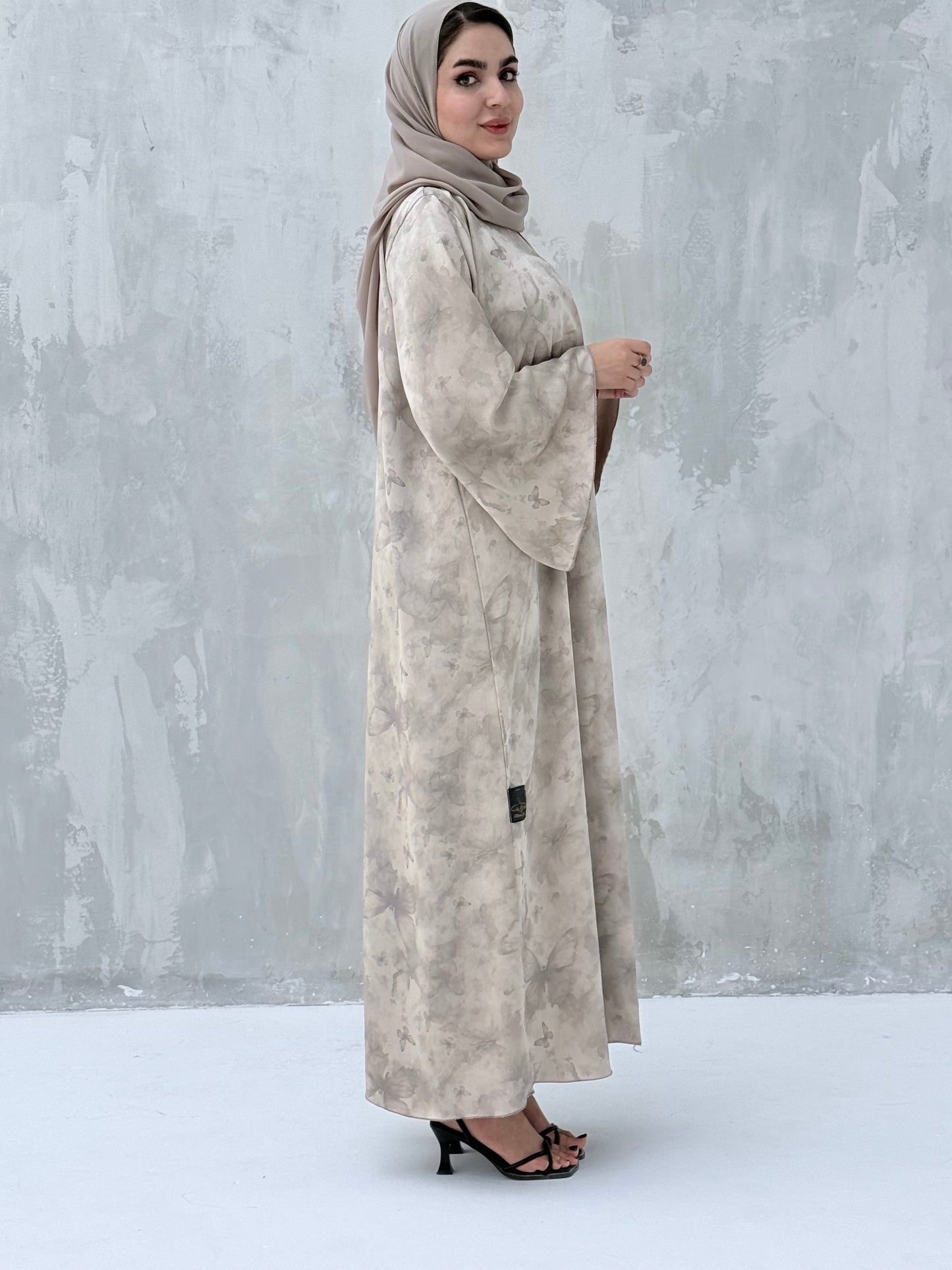 A woman wearing a Silver & Beige printed abaya with long sleeves and a round neckline.