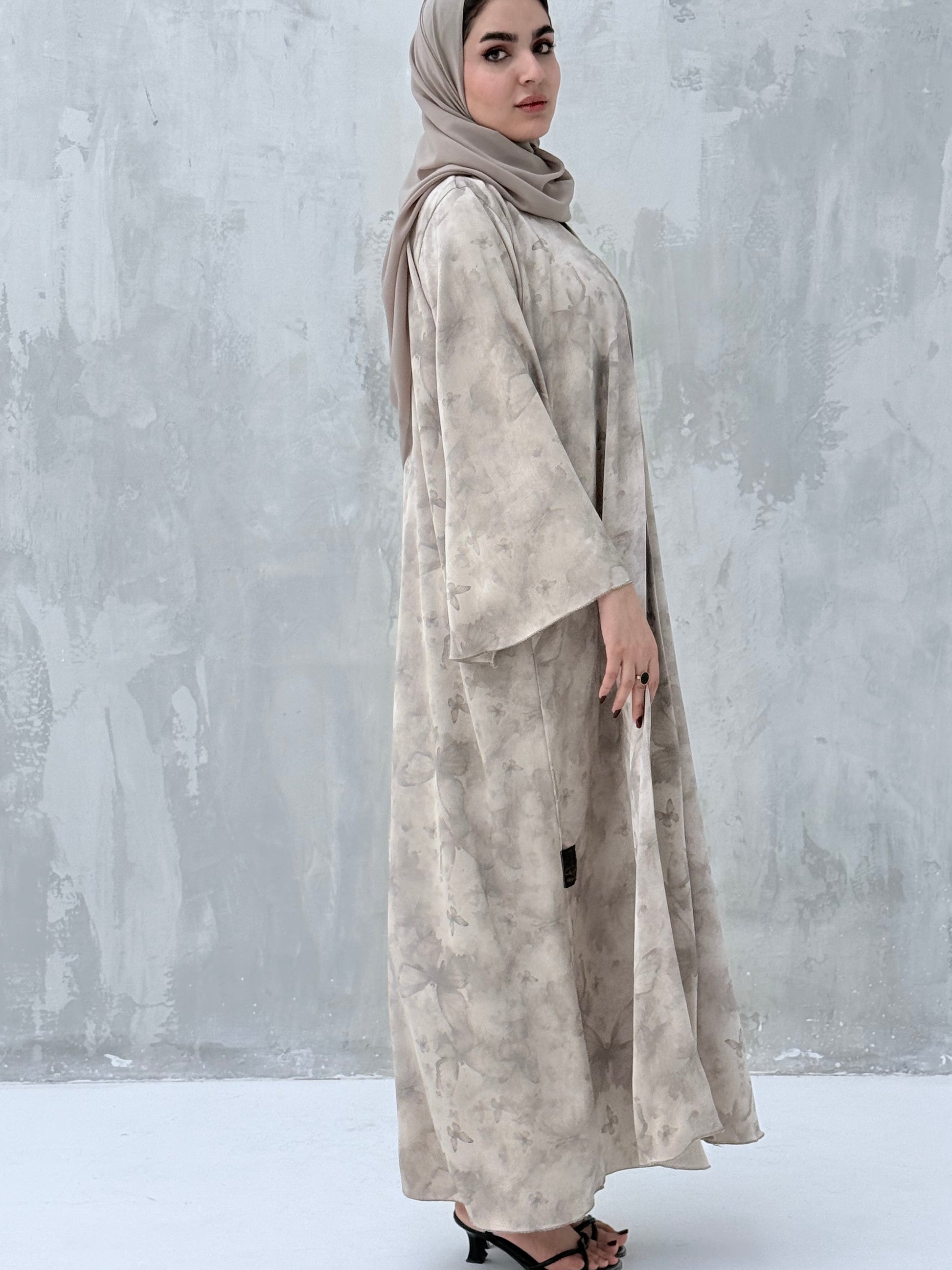 A woman wearing a Silver & Beige printed abaya with long sleeves and a round neckline.
