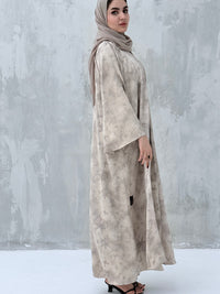 A woman wearing a Silver & Beige printed abaya with long sleeves and a round neckline.