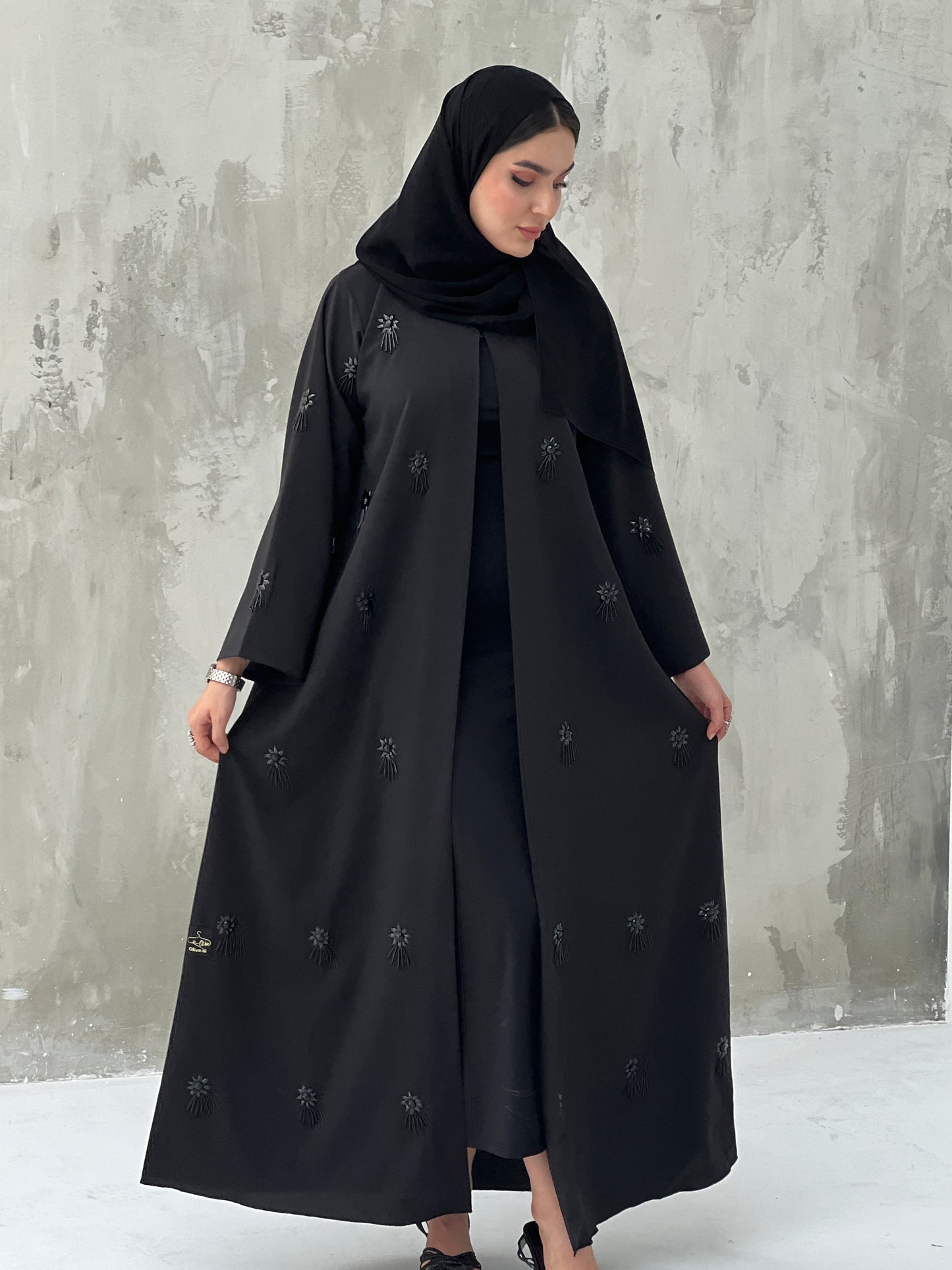 A woman wearing a Black Abaya with floral patterns Scattered Embellishments and a matching Sheila