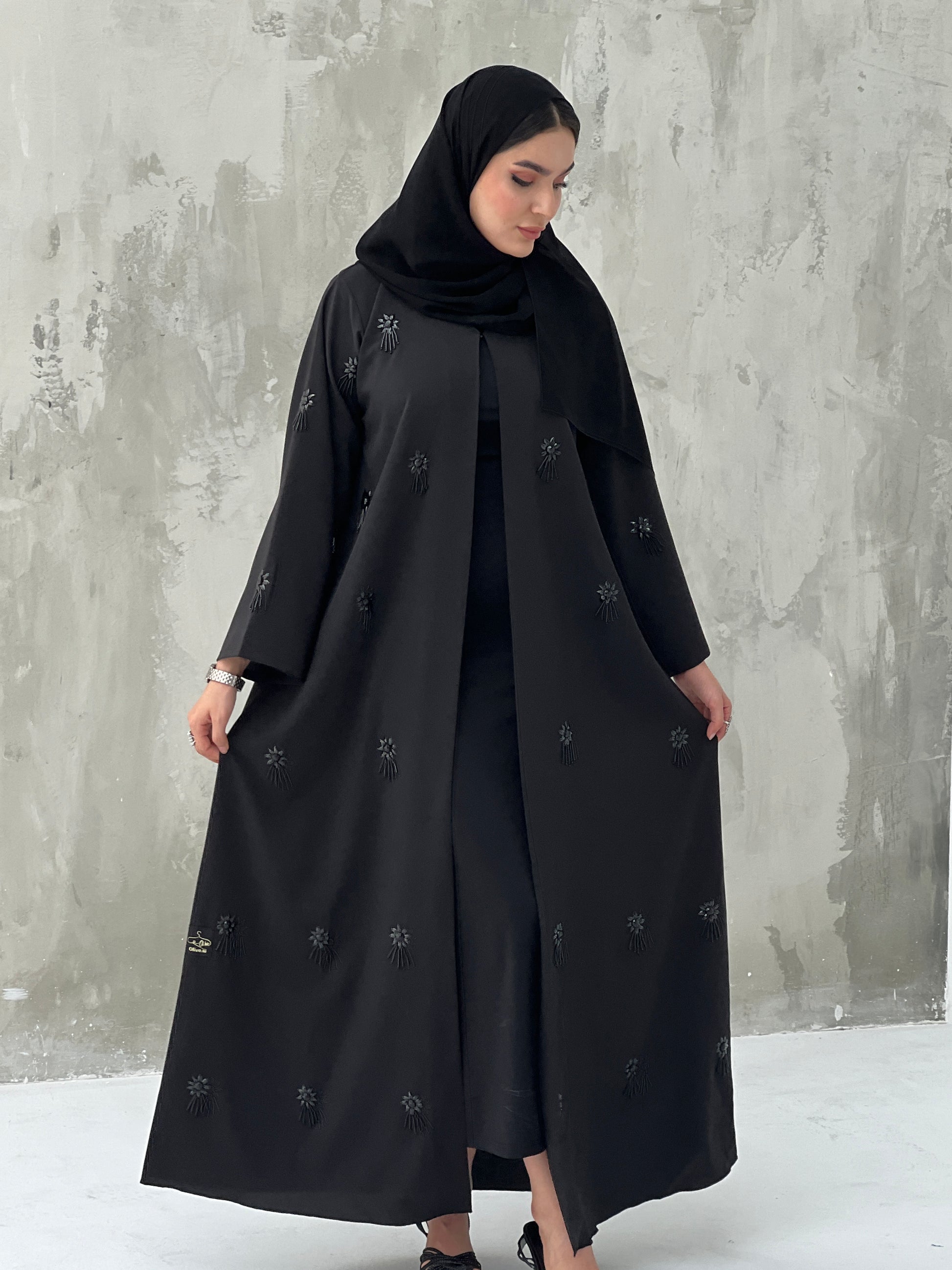 A woman wearing a Black Abaya with floral patterns Scattered Embellishments and a matching Sheila