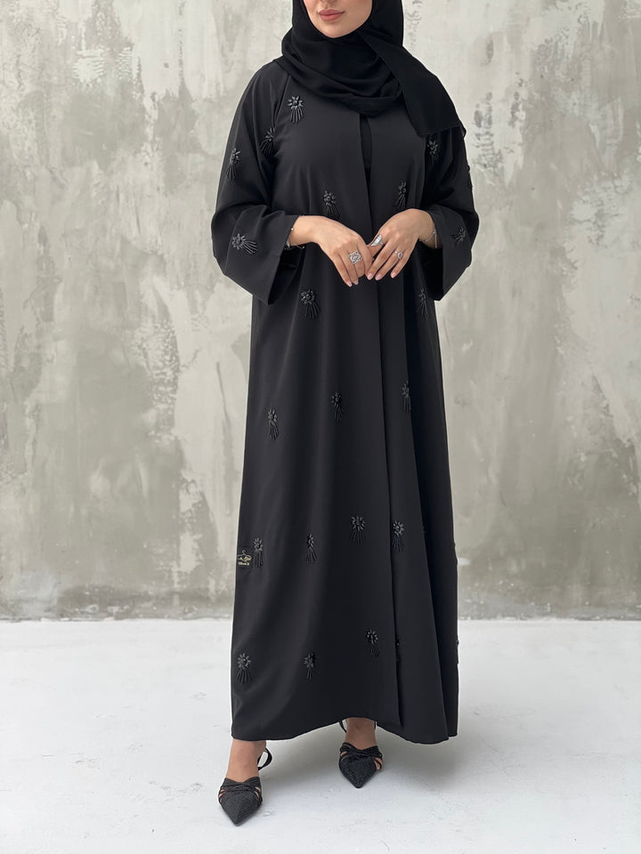 A woman wearing a Black Abaya with floral patterns Scattered Embellishments and a matching Sheila