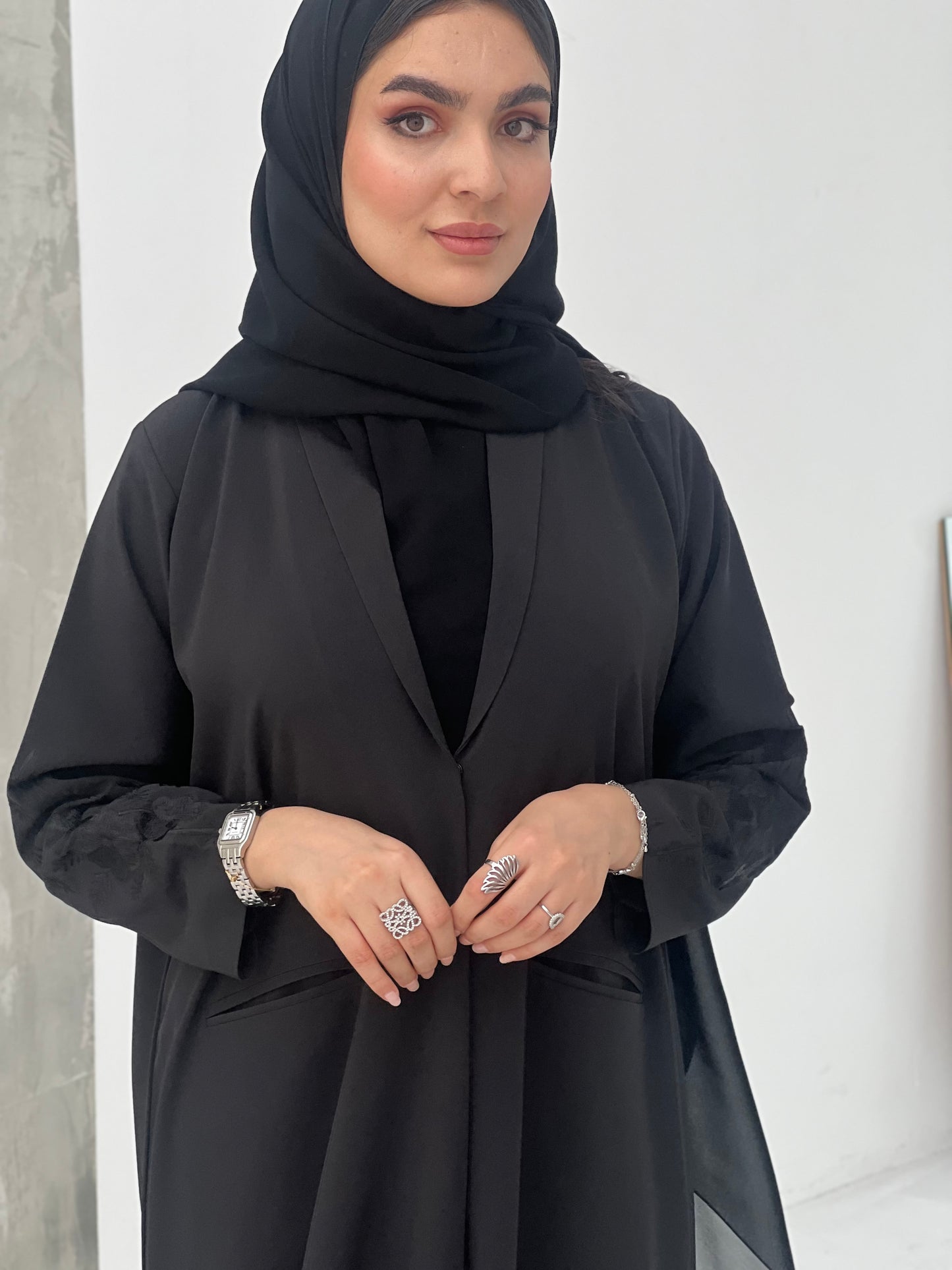 A woman wearing a Black Blazer-Style Abaya with Embroidered Sleeves with a Sheila headscarf.