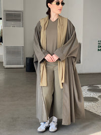 A woman wearing a Grey Cotton abaya with pants and a top, standing in a room with light decor.
