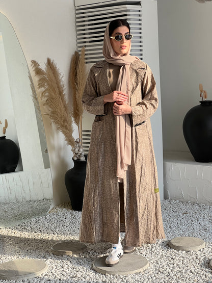 A woman wearing  a Beige Printed Trench coat style with buttons and pockets in an indoor setting
