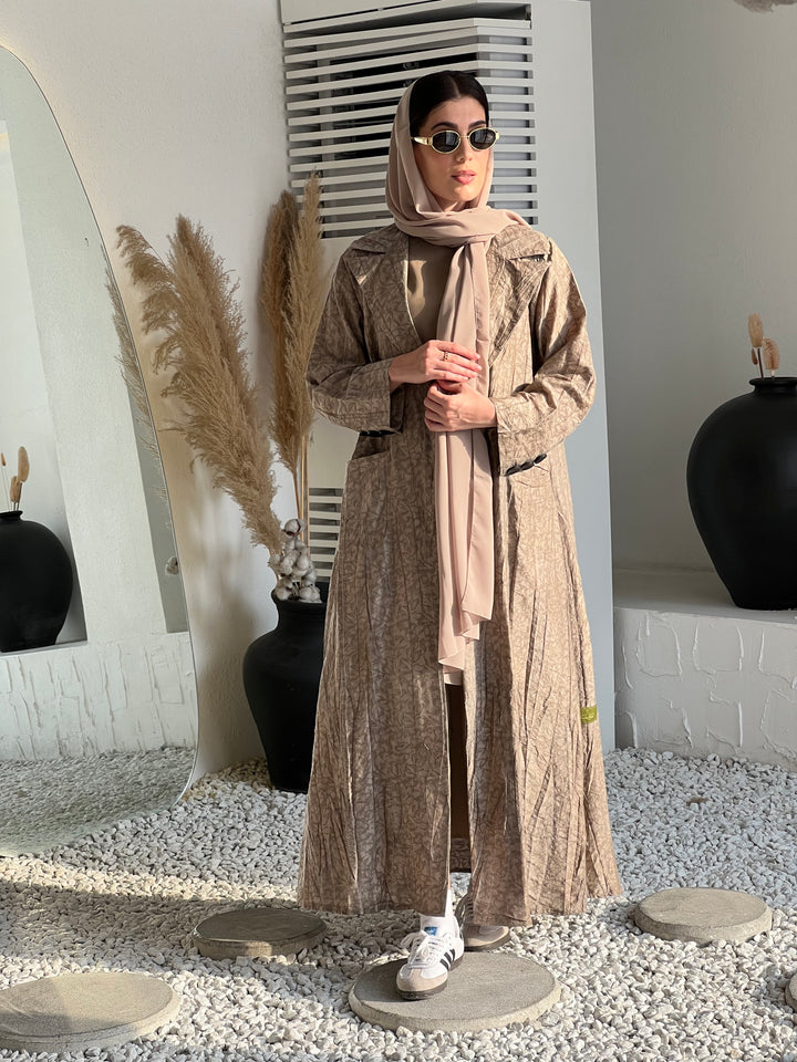 A woman wearing  a Beige Printed Trench coat style with buttons and pockets in an indoor setting