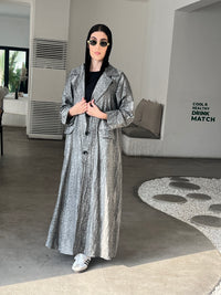 A woman wearing  a Grey Printed Trench coat style with buttons and pockets in an indoor setting