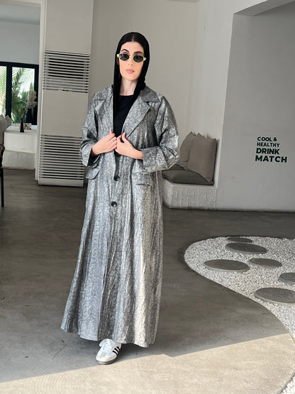 A woman wearing  a Grey Printed Trench coat style with buttons and pockets in an indoor setting