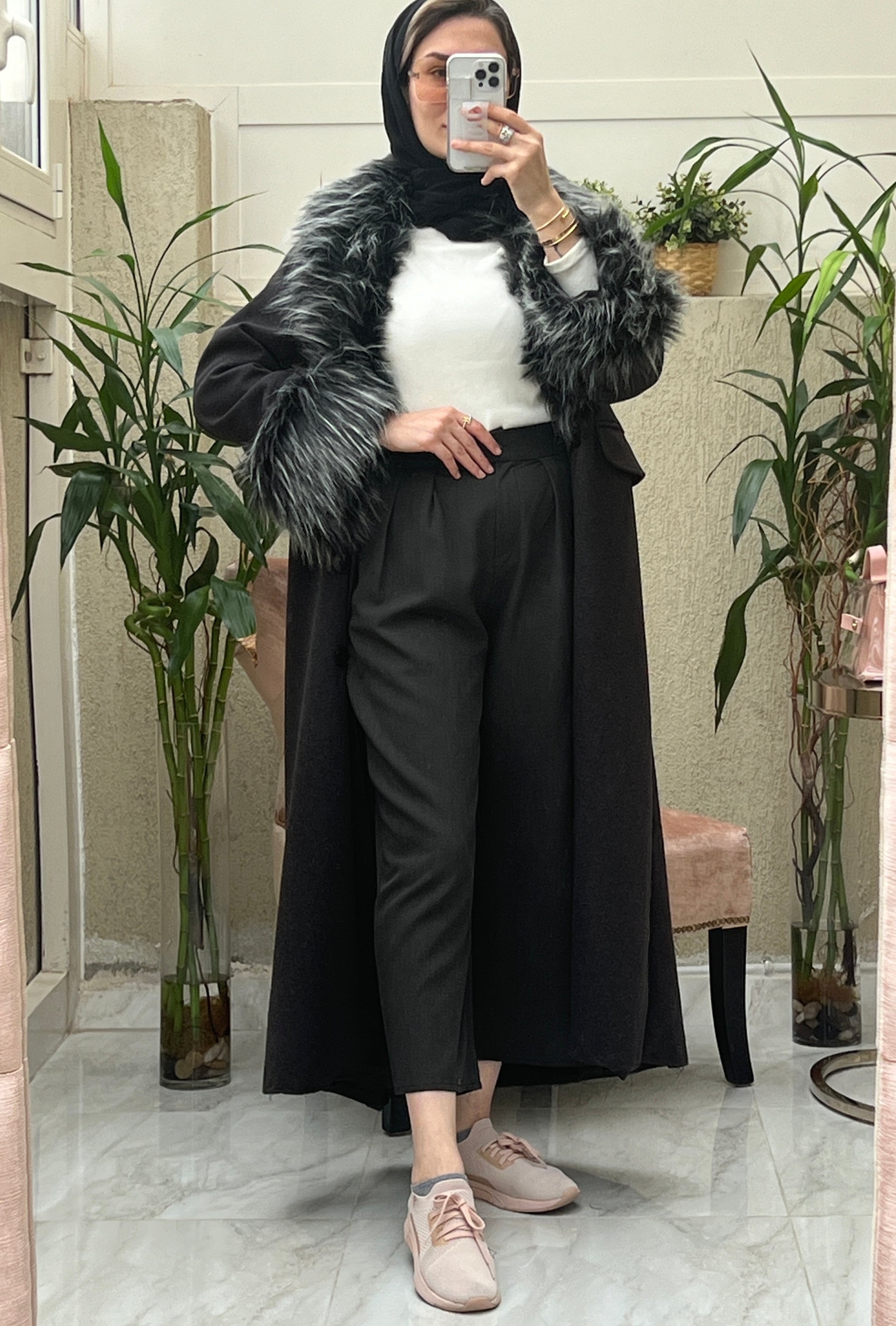 A Woman wearing a Black abaya with faux fur lining, paired with a matching Sheila headscarf